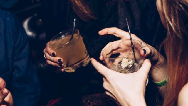 People are sitting together, holding drinks, engaging in conversation and laughter.