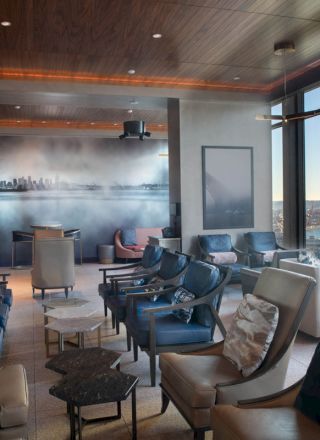 A modern lounge with comfortable seating, a cityscape mural, and large windows offering a scenic view.